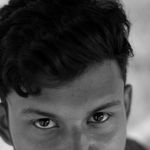 Close-up black and white portrait of a young adult male with expressive eyes.