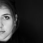 Half-face black and white portrait of a woman against a dark background.